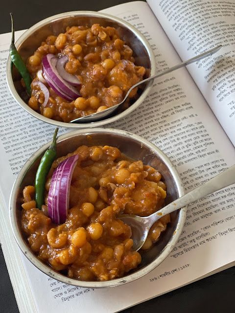 a bowl filled with beans and onions on top of an open book next to a spoon