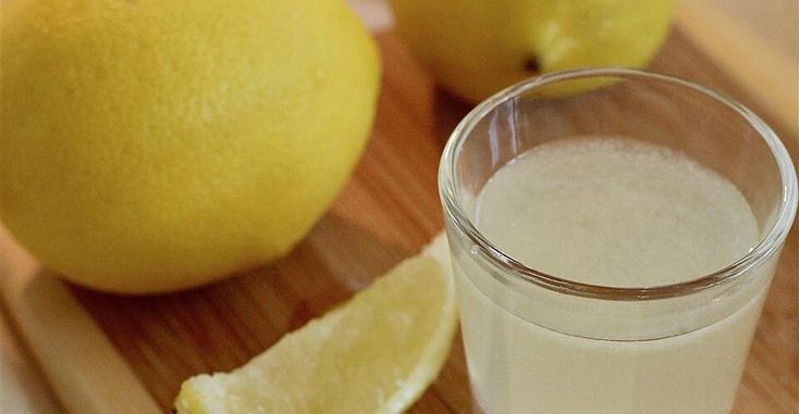 a glass of milk next to two lemons on a cutting board