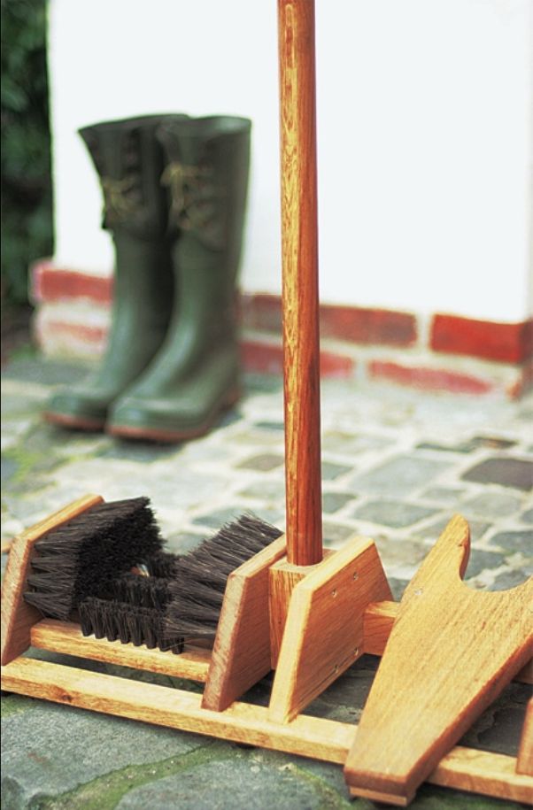 a pair of boots and brooms sitting on top of a tile floor next to a wooden pole