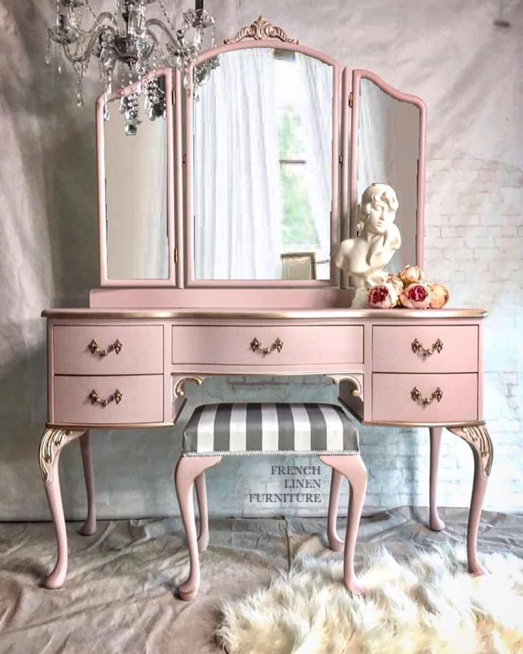 a pink vanity with a bench and mirror