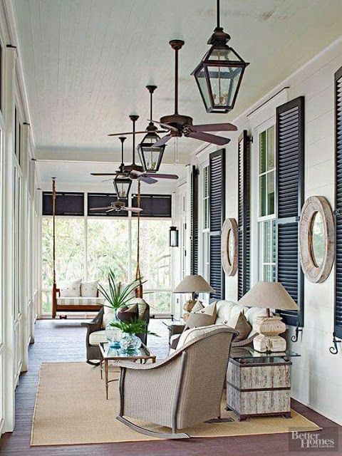 a porch with chairs and lamps on the side walk next to an open door that leads to another room