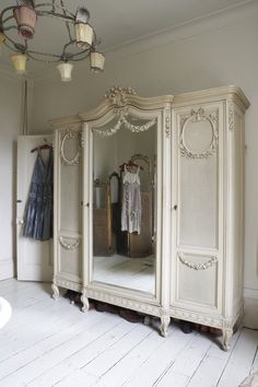 an ornate white armoire with mirrors and lights