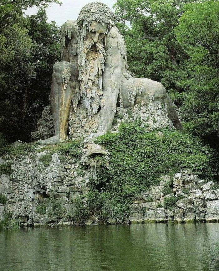 a statue of a man with a beard sitting next to a body of water