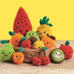 a knitted basket filled with fruit on top of a wooden table in front of a yellow background