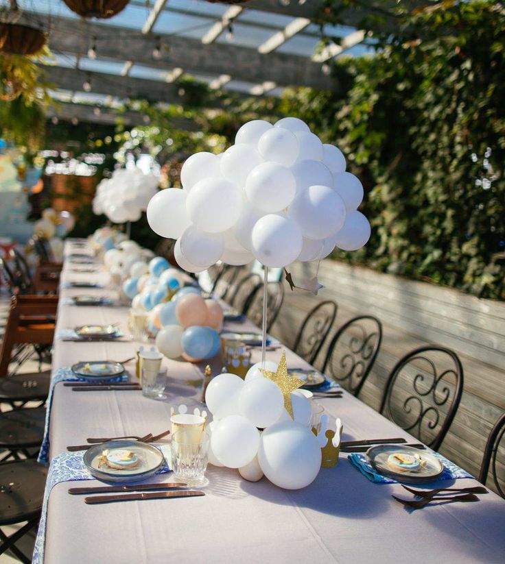 a long table with white and blue balloons on it