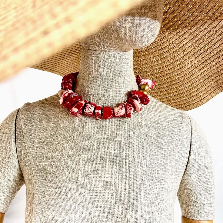 These beads are a two-tone natural Coral in red and white.  The beads are irregular, and the color is best appreciated in person.  The beads are medium size, complimented by two gold color wooden beads.  The necklace makes a statement with its simplicity, showcasing the beauty of the natural cut of the coral.  The natural stone is ideal for daytime, and the shape and design suit nighttime.  The necklace makes it easy to travel with.  The necklace measures 17 inches and weighs 8 ounces. Red Coral Beaded Necklaces With Wooden Beads, Red Coral Necklace With Wooden Beads, Red Coral Jewelry With Wooden Beads, Red Bohemian Shell Necklace For Gift, Red Polished Bead Necklaces For Beach, Beach Jewelry With Colorful Beads In Red, Red Polished Beads Necklace For Beach, Beach Red Jewelry With Colorful Beads, Red Coral Beaded Necklace With Wooden Beads