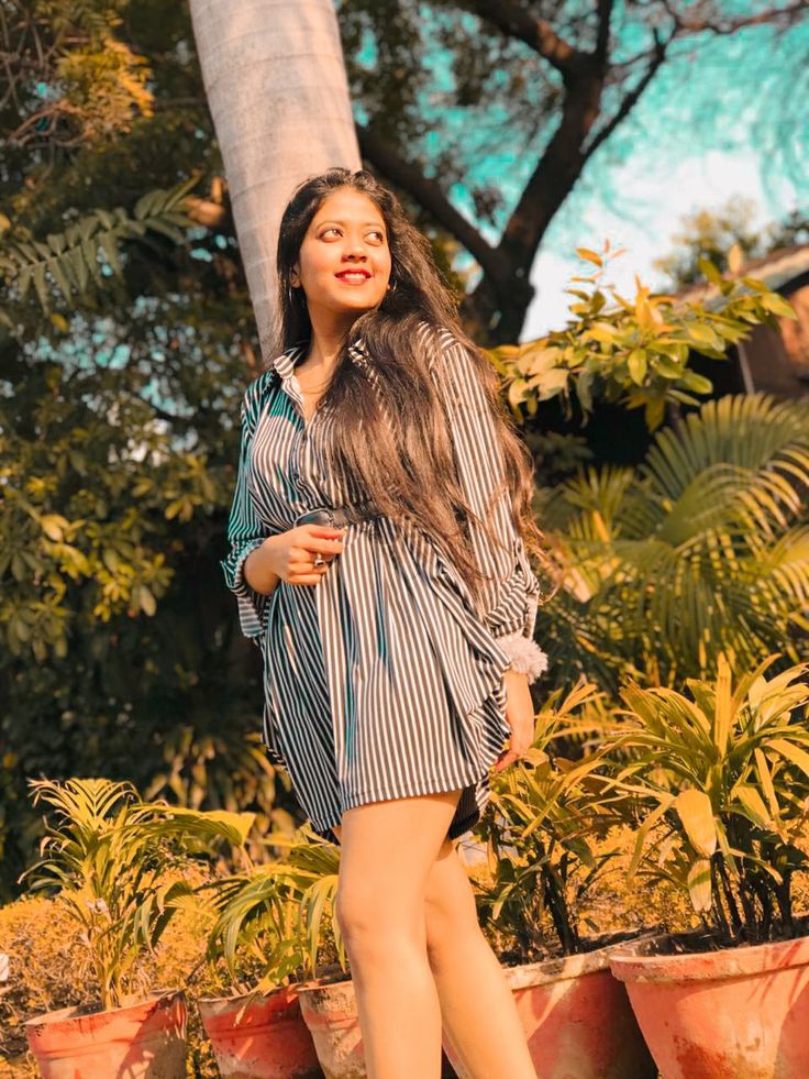 a woman standing in front of potted plants and looking off to the side with long hair