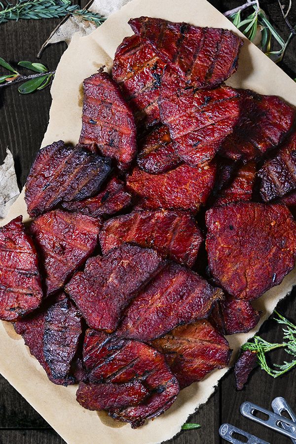 sliced up meat sitting on top of a table next to herbs and utensils