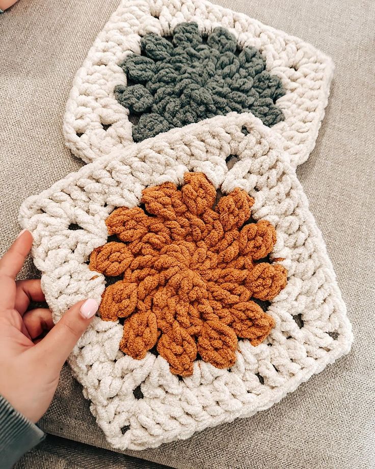 two crocheted coasters on a couch being held by someone's hand