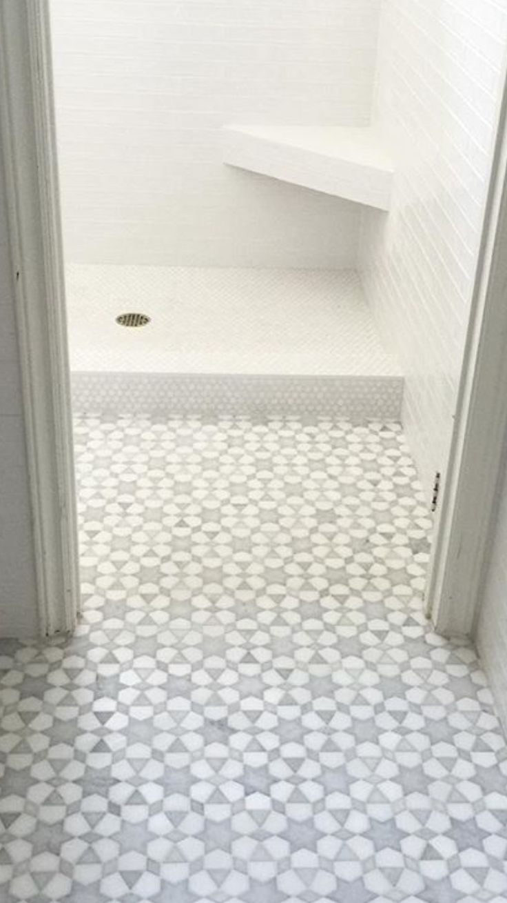 an open door leading to a bathroom with white tile and hexagonal pattern on the floor