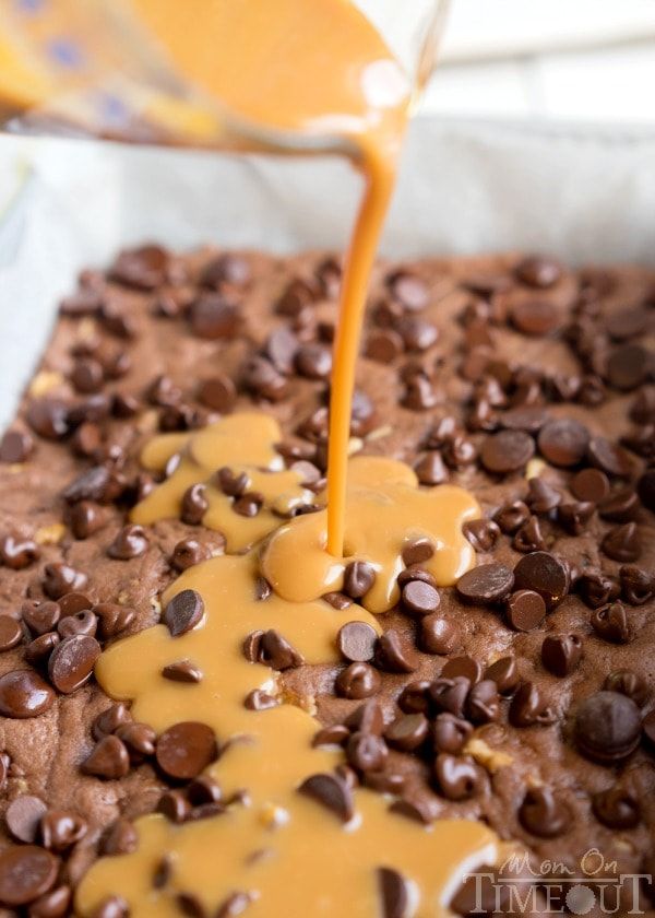 chocolate cake with caramel drizzle being poured on top and topped with chocolate chips