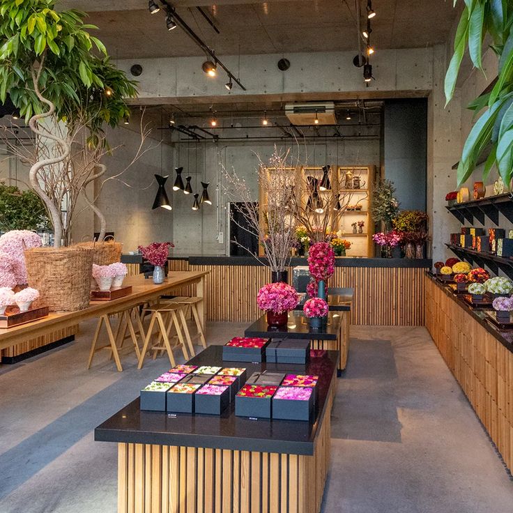 a store filled with lots of wooden tables covered in pink and purple flowers next to plants