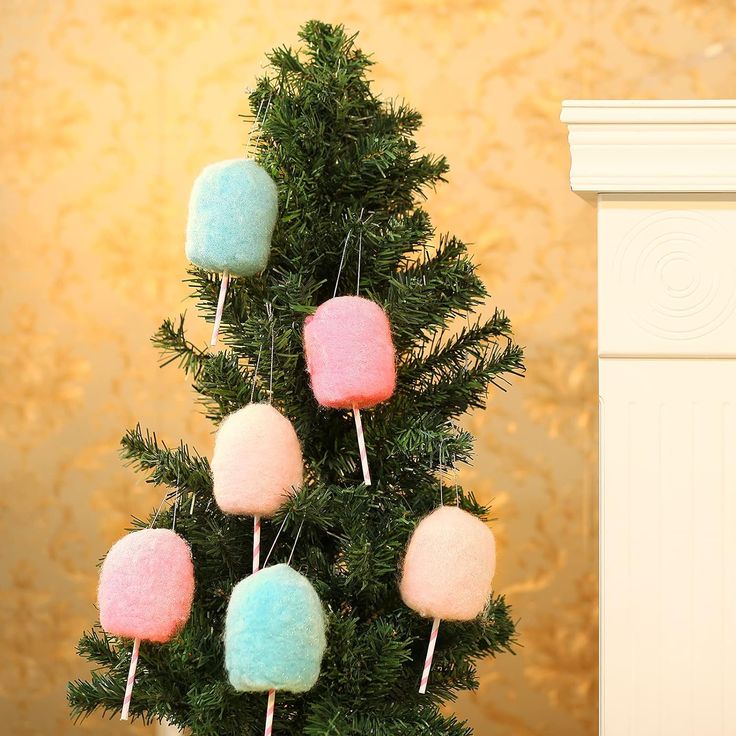 a small christmas tree decorated with marshmallows and lollipops in pastel colors