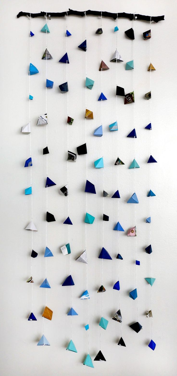 a wall hanging made out of different colored triangles on it's sides and strings