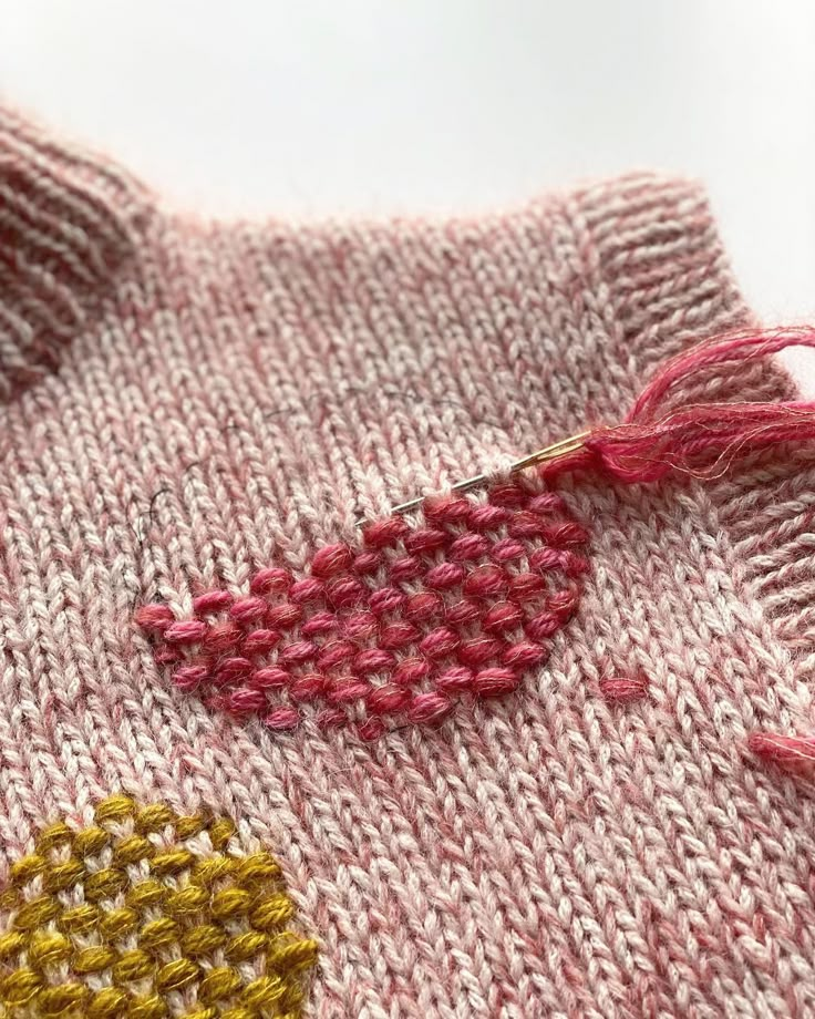 a knitted sweater with pink and yellow details