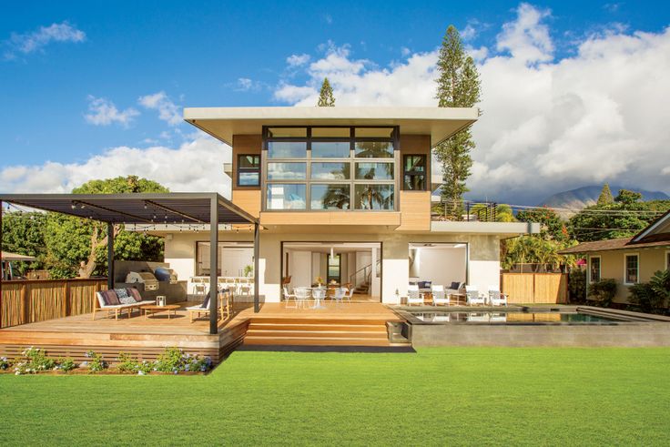 a modern house with an outdoor deck and covered patio area in the foreground on a sunny day