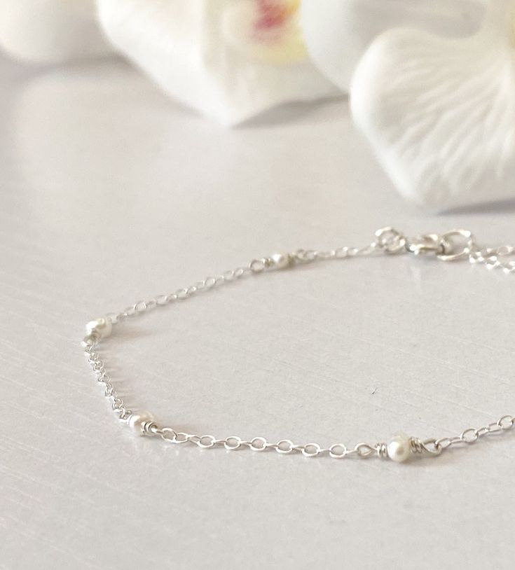 "This beautifully simple bracelet is lovingly handmade with a six tiny Freshwater Pearls and a choice of 14k Gold Filled, 14k Rose Gold Filled or Sterling Silver Chain. M A T E R I A L S: * Freshwater Pearl * 14k Gold Filled, 14k Rose Gold Filled or Sterling Silver Chain S I Z E: *  Gemstones - Approximately 2-3mm *  Chain Thickness - Approximately 1.1mm  All of our jewellery is carefully handmade using good quality materials and handpicked gemstones, with the aim to produce quality pieces that you can love & wear for years to come.  P E A R L: * June Birthstone * Talisman for Gemini, Cancer * Third Eye Chakra Pearl signifies faith, charity and innocence.  It enhances personal integrity and helps to provide a focus to ones attention.  Pearl symbolises purity and is known as a \"stone of si Delicate Sterling Silver Bracelet Jewelry, Minimalist Sterling Silver Pearl Bracelet, Dainty Stackable Pearl Bracelet For Everyday, Minimalist Sterling Silver Pearl Bracelet For Wedding, Delicate Sterling Silver Chain Bracelet For Anniversary, Silver Dainty Birthstone Bracelets, Dainty Sterling Silver Pearl Bracelet, Everyday Delicate Sterling Silver Pearl Bracelet, Elegant Stackable Sterling Silver Bracelet As Gift