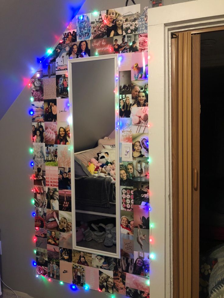 a mirror is decorated with lights and pictures on the wall next to a bed in a bedroom