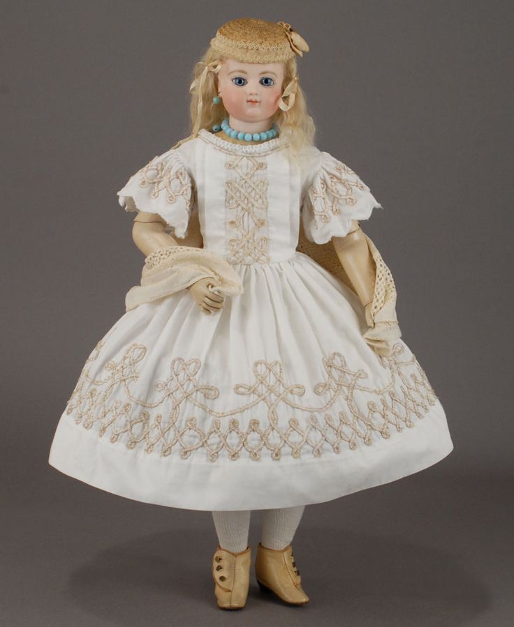 a doll is wearing a white dress with gold trim