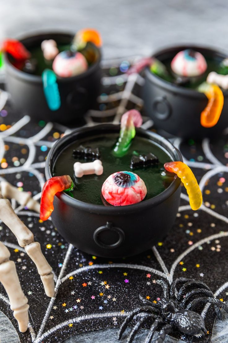 halloween candies in black containers with candy on the top and sprinkles around them