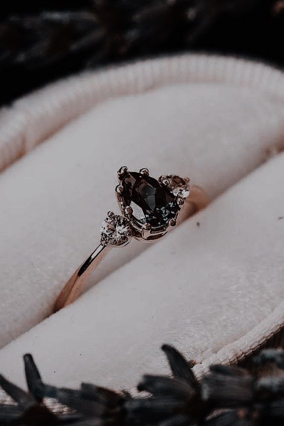 an engagement ring is sitting in a velvet box with black and white stones on it