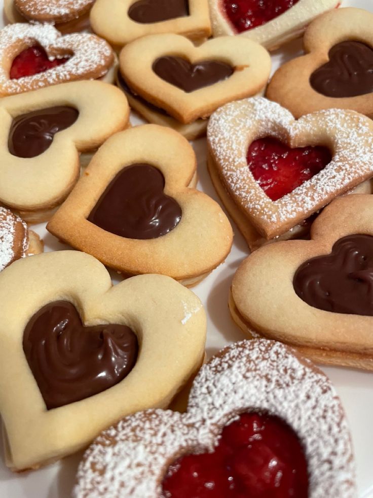 heart shaped linzer shortbread cookies with strawberry jam and chocolate ganache Heart Shape Jam Cookies, Cookies Jam Heart, Heart Shaped Cookies With Jam, Heart Shaped Tarts, Linzer Cookies Aesthetic, Heart Shaped Thumbprint Cookies, Heart Shaped Pastries, February Baking Ideas, Shortbread Aesthetic