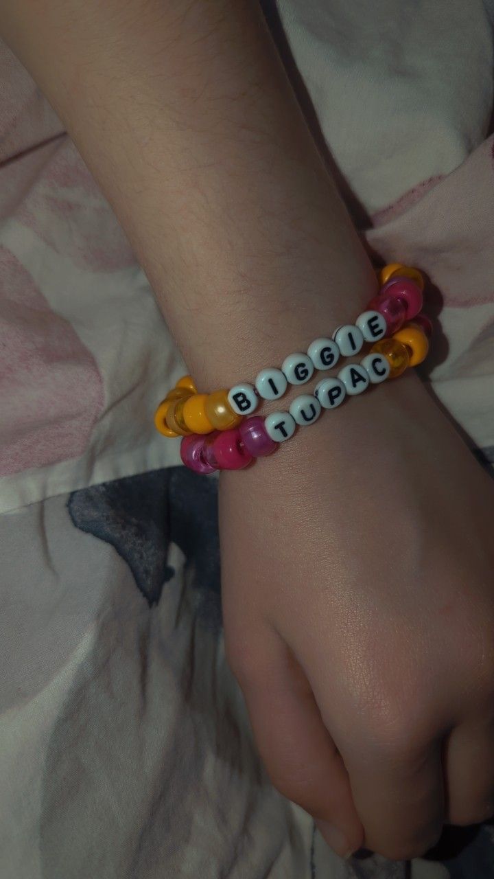 a child's hand wearing a bracelet with words written on it and beads around the wrist