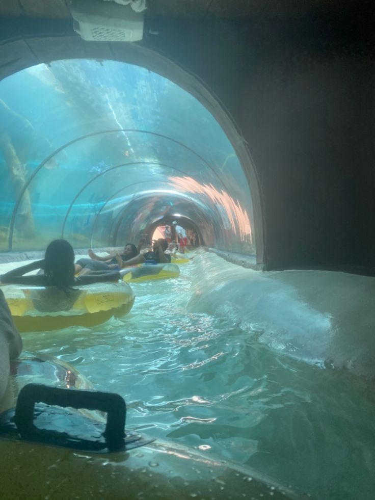 people are swimming in the water inside a tunnel with an artificial underwater pool on one side