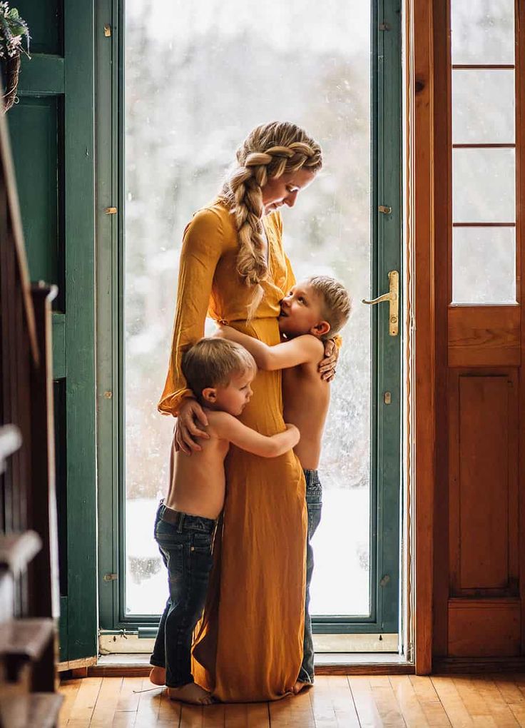 a woman and two children hugging each other in front of a door