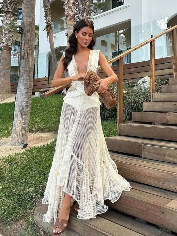 Experience effortless elegance in the Fringe and Mesh Cutout Maxi Dress. Featuring a deep V-neckline, irregular ruffled details, and a sleeveless design, this dress exudes modern sophistication. The hollow out and tassel accents add a touch of playful flair, making it the perfect choice for any fashion-forward woman. Party V-neck Maxi Dress With Ruffled Skirt, Elegant Sleeveless V-neck Dress For Beach, Beach V-neck Ruffled Maxi Dress, Summer V-neck Dress With Ruffled Skirt, Elegant V-neck Maxi Dress With Ruffled Skirt, Elegant Beige Sleeveless Dress With Ruffles, Chic Asymmetrical Summer Wedding Dress, Chic Summer Wedding Asymmetrical Dress, V-neck Cocktail Dress With Ruffled Skirt