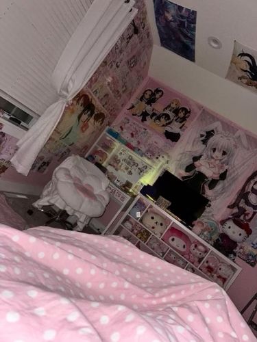 a bedroom with pink and white polka dot bedspread, posters on the wall