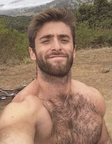 a shirtless man with no shirt standing in front of a mountain and looking at the camera