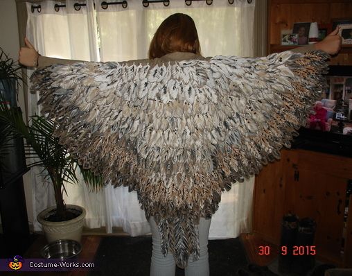 a woman standing in front of a window covered in bird feathers