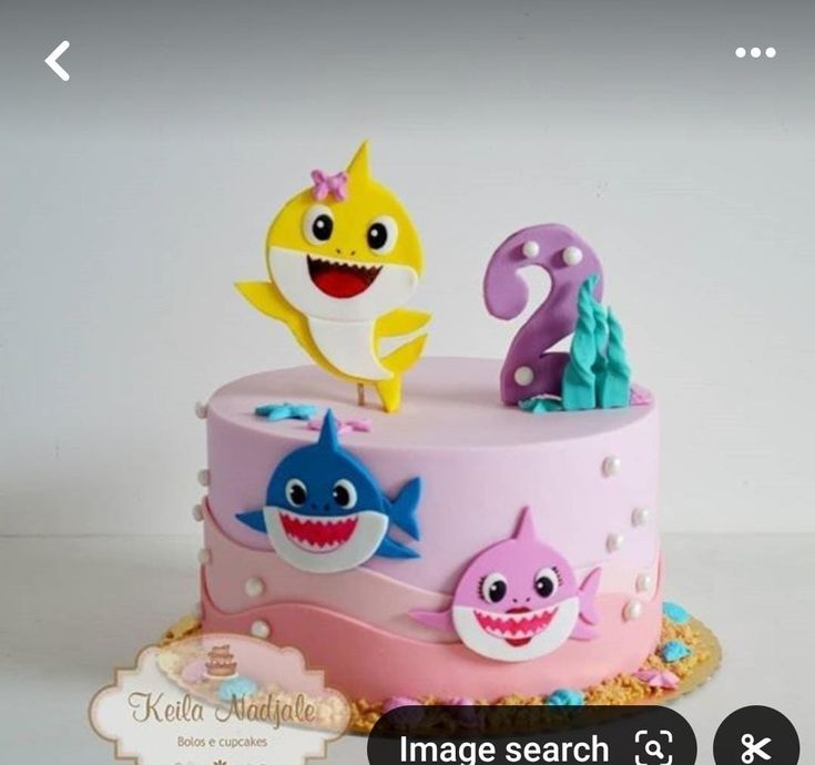 a birthday cake with three little sharks on top and one big shark on the bottom