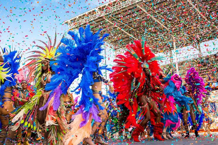 colorfully dressed people walking down the street in front of a stage with confetti