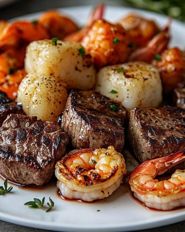 steak, shrimp and scallops on a white plate