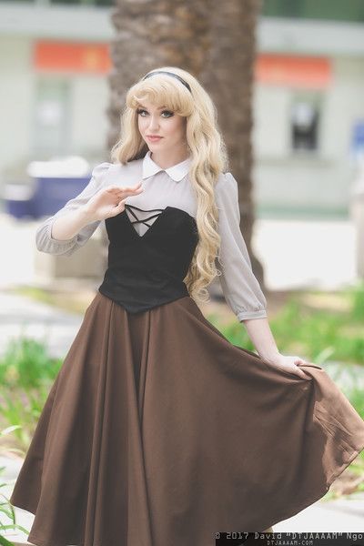 a woman with long blonde hair wearing a brown and black dress is posing for the camera