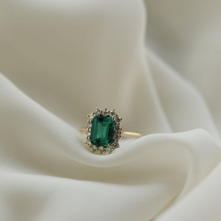 Maggie – Olive Avenue Jewelry Heirloom Style Emerald Ring With Halo, Heirloom Emerald Ring With Halo, Heirloom Style Emerald Ring With Halo For Formal Occasions, Elegant Green Emerald Ring With Halo Setting, Elegant Green Gemstone Halo Ring, 14k Gold Green Emerald Ring With Halo, Classic Emerald Cut Halo Emerald Ring, Timeless Emerald Ring With Radiant Cut, Green Emerald Cut 14k Gold Cluster Ring