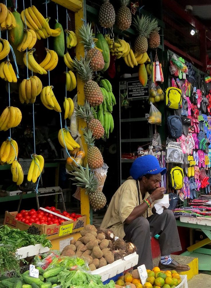 a man sitting in front of a fruit stand