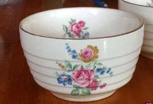 two white bowls with pink and blue flowers on them sitting on a wooden table top