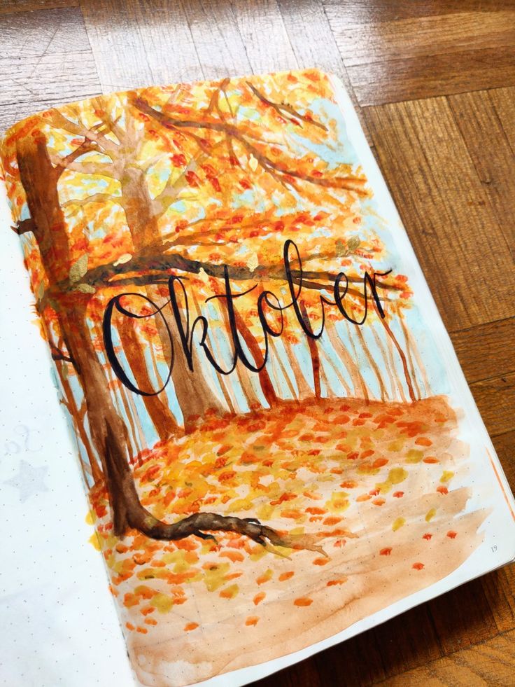 an art journal with the word october written in black ink on it, sitting on a wooden floor