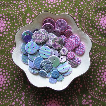 a bowl filled with lots of different colored buttons on top of a green table cloth