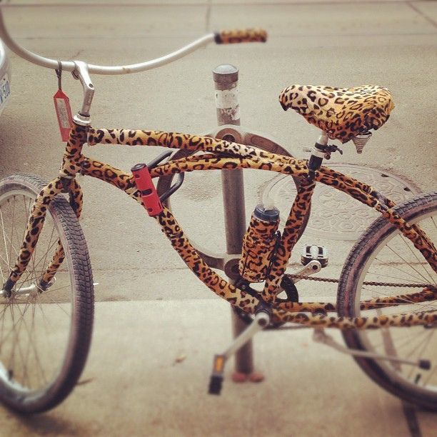 a leopard print bicycle parked next to a parking meter