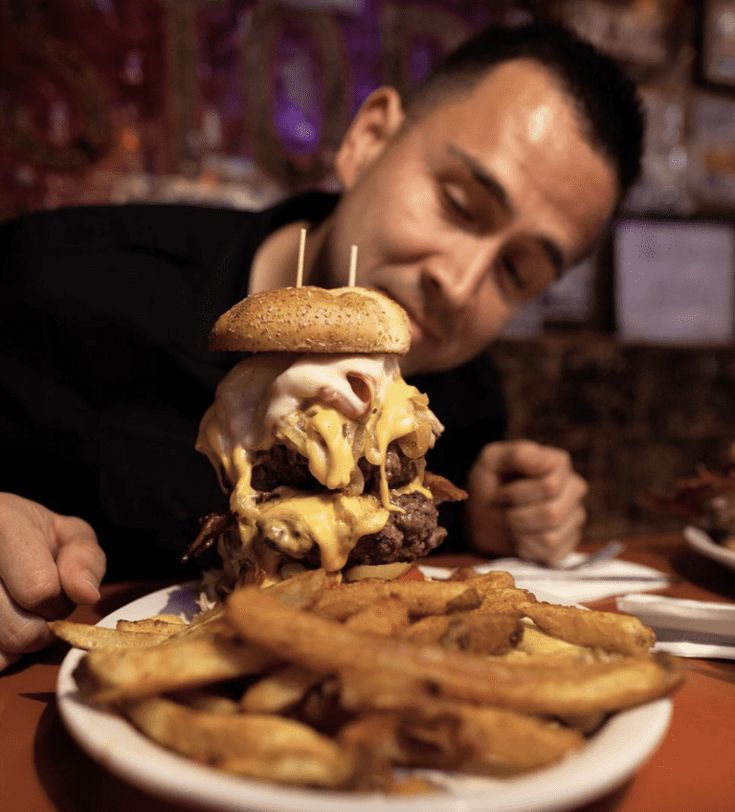 a man sitting at a table with a hamburger and french fries in front of him