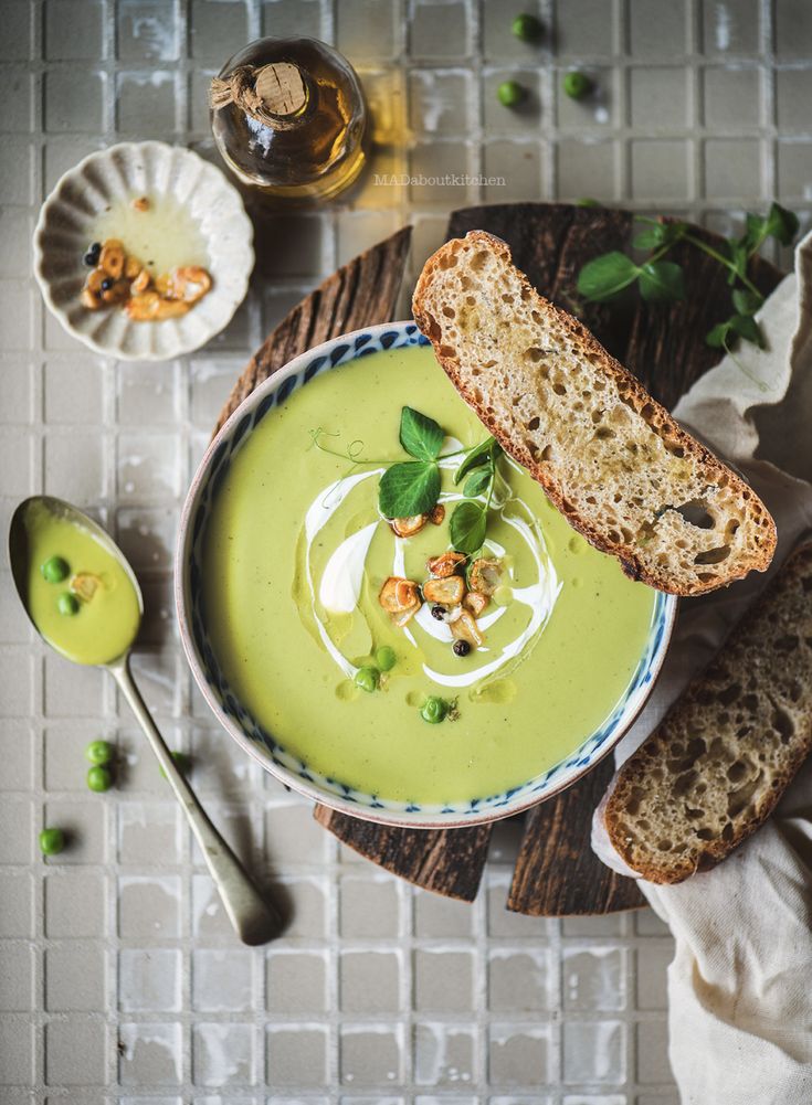 a bowl filled with green soup next to two slices of bread