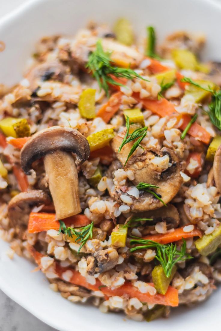 a white bowl filled with rice, mushrooms and veggies on top of a table