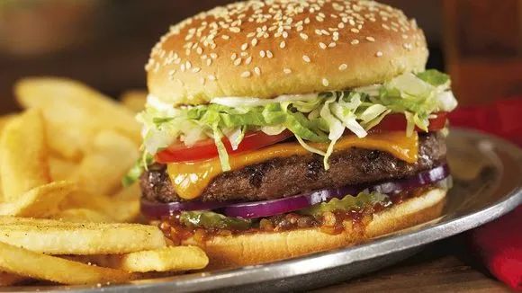 a cheeseburger with lettuce, tomato and onion on a plate next to french fries