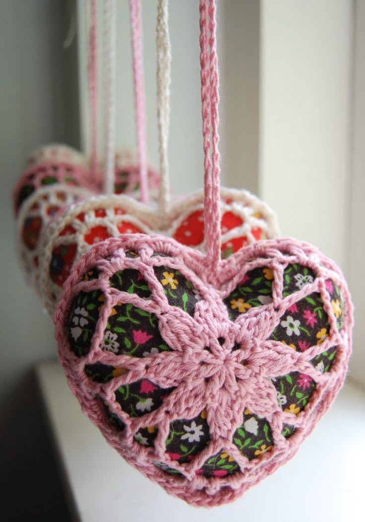 a crocheted heart hanging from a window sill