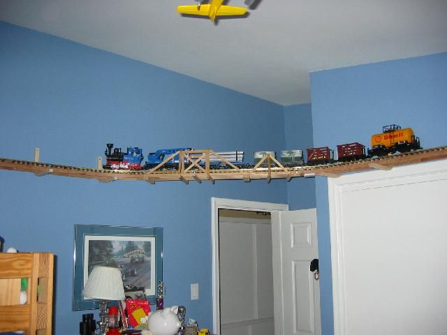 a toy train set is on top of a wooden bridge in a child's bedroom