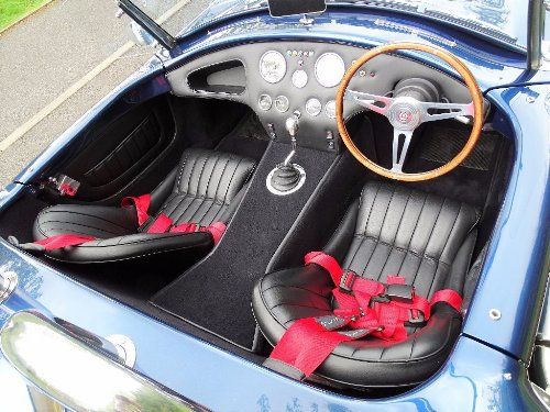 the interior of a blue sports car with black leather seats and red bows on the steering wheel